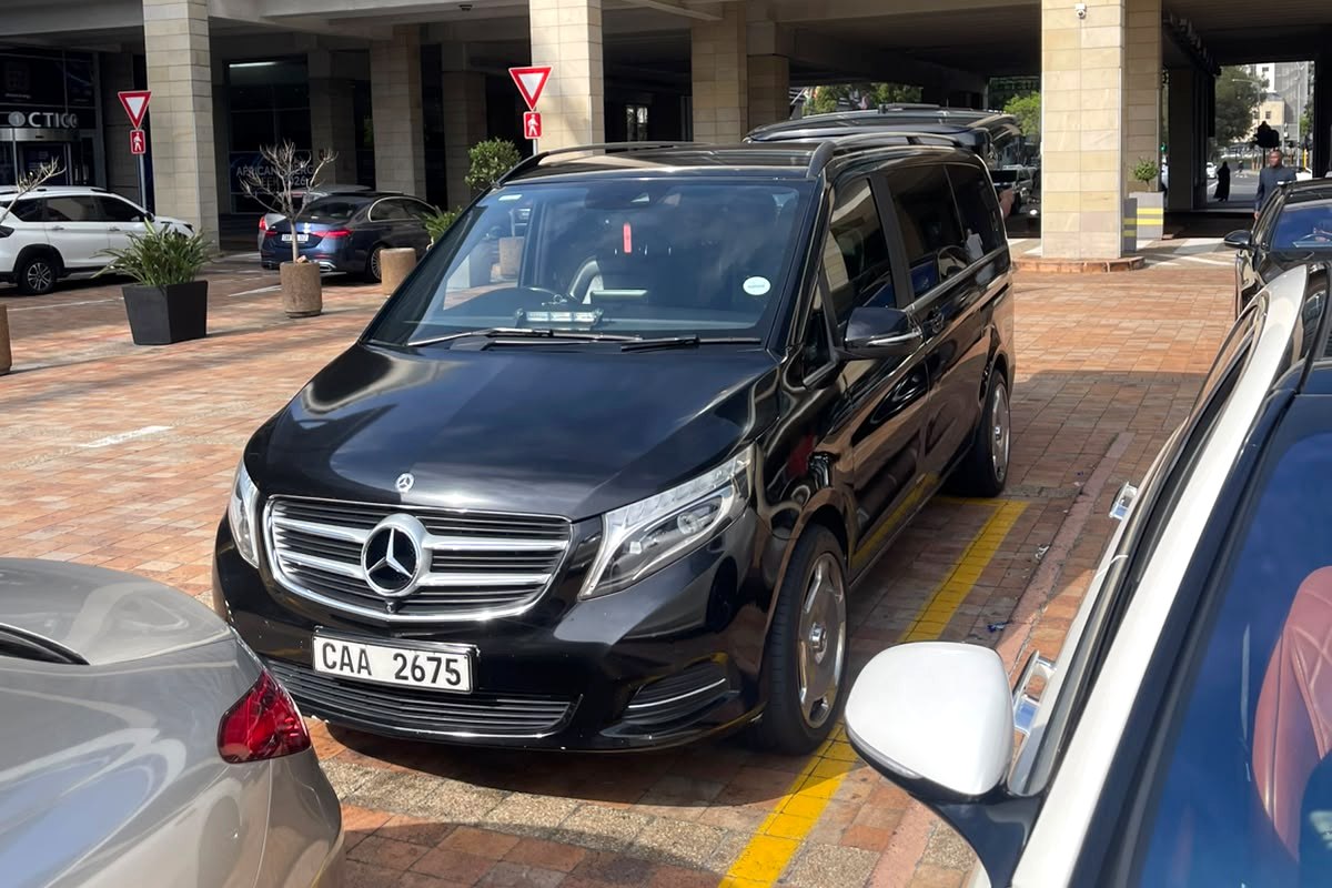 Black Mercedes V-Class van parked at a hotel entrance